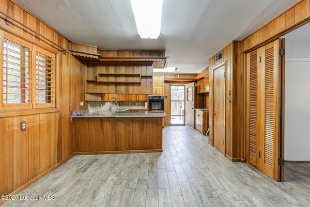3413 42nd St, Lubbock, TX 79413 - kitchen featuring black oven, open shelves, brown cabinetry, a peninsula, and a sink