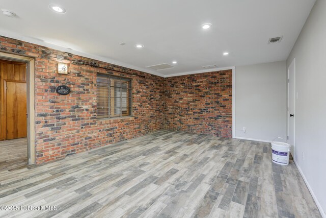 3413 42nd St, Lubbock, TX 79413 - empty room featuring wood finished floors, brick wall, baseboards, recessed lighting, and a smoke detector