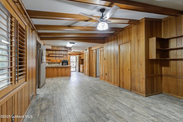3413 42nd St, Lubbock, TX 79413 - unfurnished living room featuring wood walls, beam ceiling, a ceiling fan, and light wood-style floors