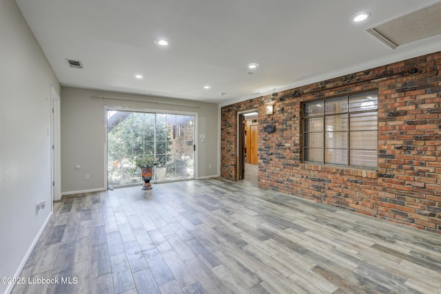 3413 42nd St, Lubbock, TX 79413 - unfurnished living room with brick wall, baseboards, wood finished floors, and recessed lighting