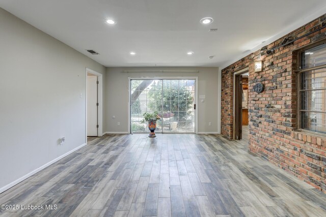 3413 42nd St, Lubbock, TX 79413 - unfurnished room with brick wall, baseboards, wood finished floors, and recessed lighting