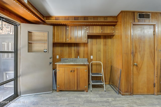 3413 42nd St, Lubbock, TX 79413 - kitchen featuring brown cabinets, light wood-style flooring, wood walls, and light countertops