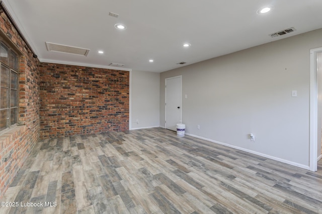 3413 42nd St, Lubbock, TX 79413 - empty room featuring wood finished floors, attic access, recessed lighting, baseboards, and brick wall