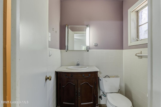 3413 42nd St, Lubbock, TX 79413 - half bathroom with tile walls, toilet, vanity, and a wainscoted wall
