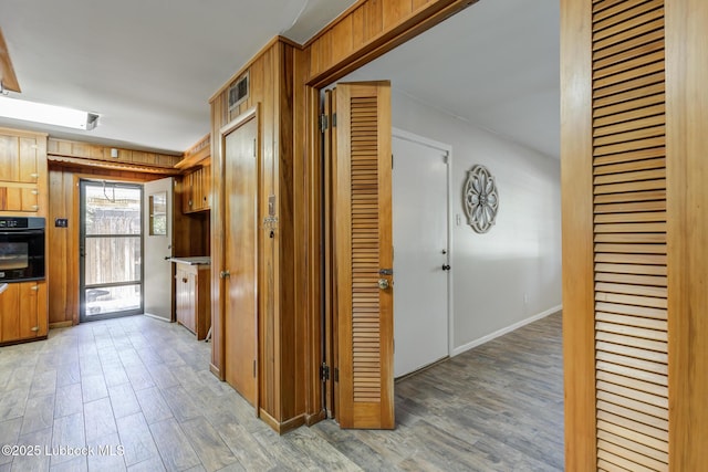 3413 42nd St, Lubbock, TX 79413 - hall featuring light wood-style flooring, wood walls, and baseboards