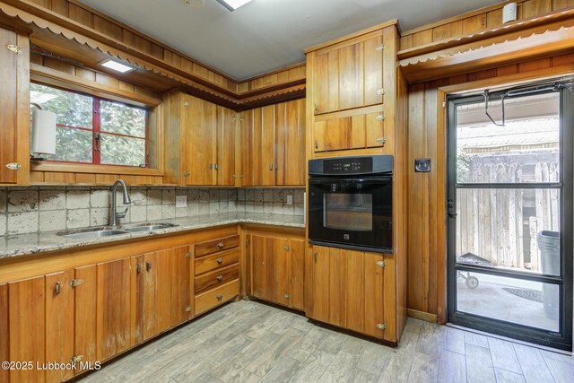 3413 42nd St, Lubbock, TX 79413 - kitchen featuring black oven, a sink, decorative backsplash, and brown cabinets