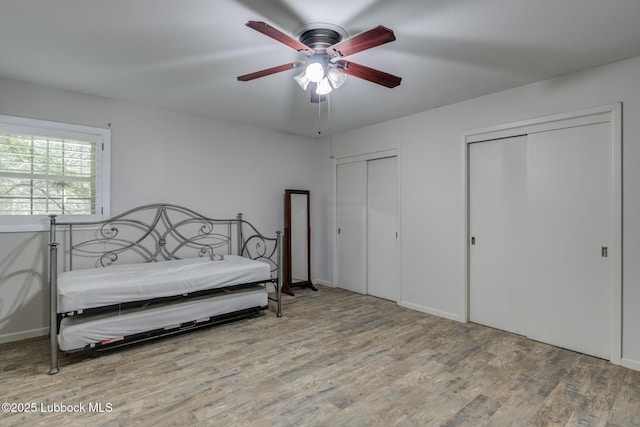 3413 42nd St, Lubbock, TX 79413 - bedroom featuring multiple closets, wood finished floors, a ceiling fan, and baseboards