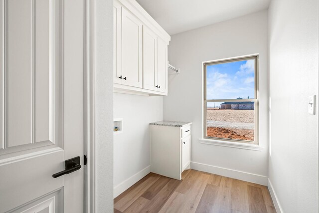 clothes washing area featuring cabinets, washer hookup, and light hardwood / wood-style floors