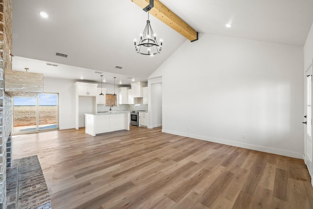 unfurnished living room with sink, high vaulted ceiling, light wood-type flooring, a notable chandelier, and beam ceiling