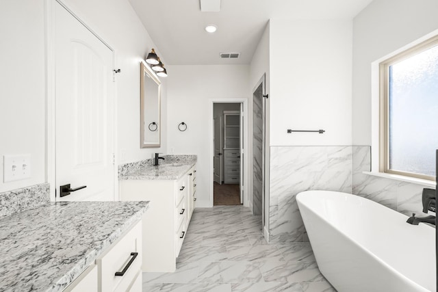 bathroom featuring vanity, tile walls, and a tub to relax in