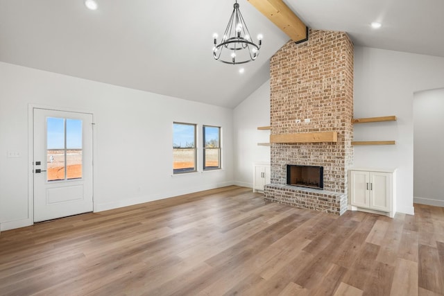 unfurnished living room featuring a brick fireplace, beam ceiling, a wealth of natural light, and light hardwood / wood-style floors