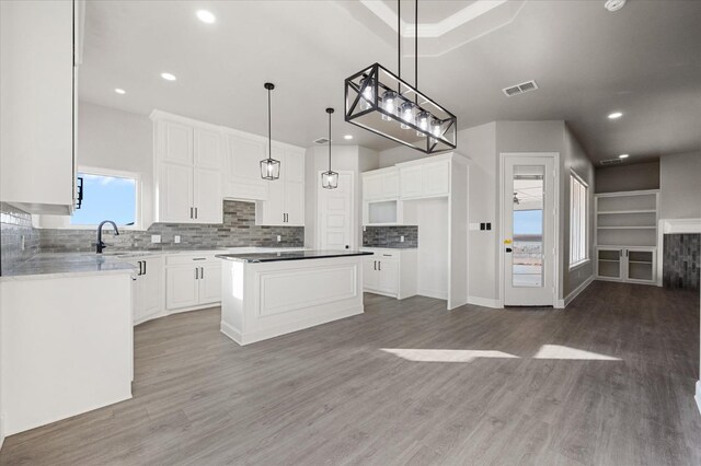 kitchen with pendant lighting, sink, white cabinets, a center island, and dark wood-type flooring