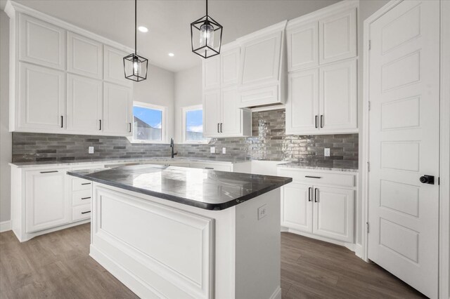 kitchen with a kitchen island, sink, white cabinets, hanging light fixtures, and dark wood-type flooring