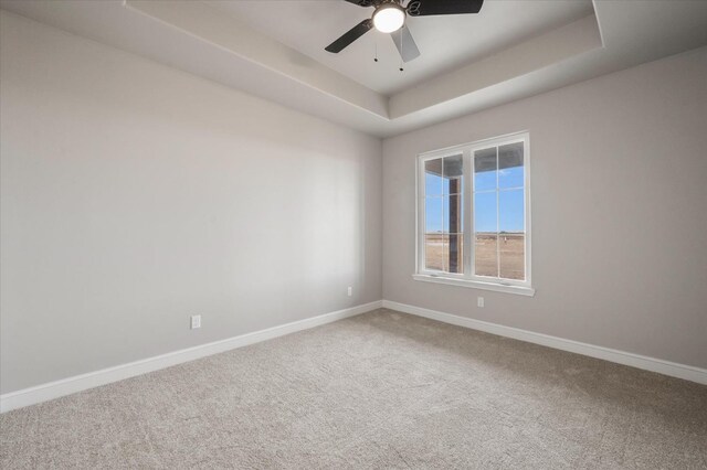 unfurnished room with ceiling fan, a tray ceiling, and carpet floors