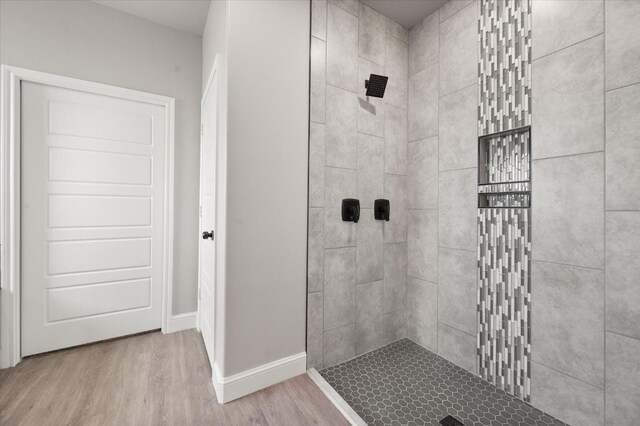 bathroom featuring wood-type flooring and a tile shower