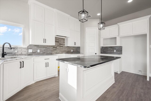 kitchen featuring hanging light fixtures, sink, a kitchen island, and white cabinets