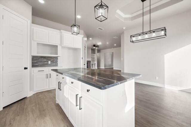 kitchen with a center island, hanging light fixtures, white cabinets, ceiling fan, and backsplash