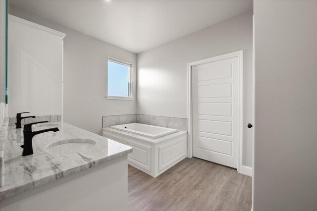 bathroom featuring vanity, hardwood / wood-style floors, and a tub