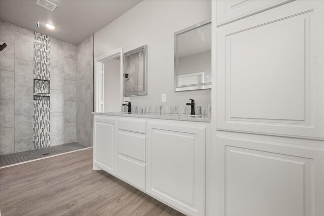 bathroom featuring tiled shower, vanity, and hardwood / wood-style floors