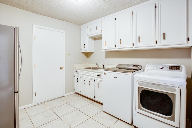 laundry room with light tile patterned flooring, sink, a textured ceiling, and washing machine and dryer