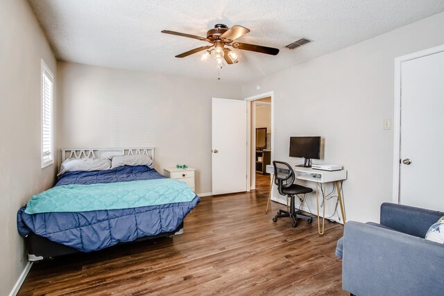 bedroom with ceiling fan, dark wood-type flooring, and a textured ceiling