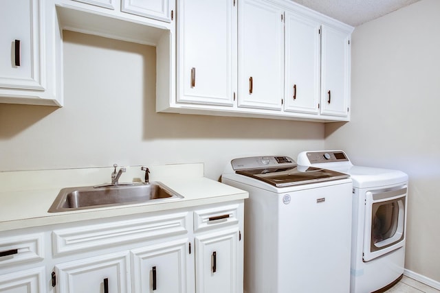 clothes washing area with cabinets, sink, and washer and dryer