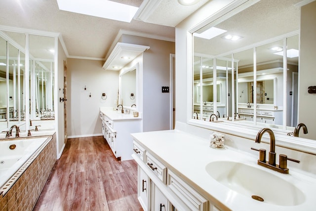 bathroom with a skylight, hardwood / wood-style flooring, vanity, a relaxing tiled tub, and crown molding