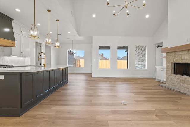 kitchen featuring a fireplace, decorative light fixtures, tasteful backsplash, white cabinetry, and a notable chandelier