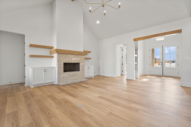 unfurnished living room with high vaulted ceiling, a fireplace, light hardwood / wood-style flooring, a chandelier, and french doors