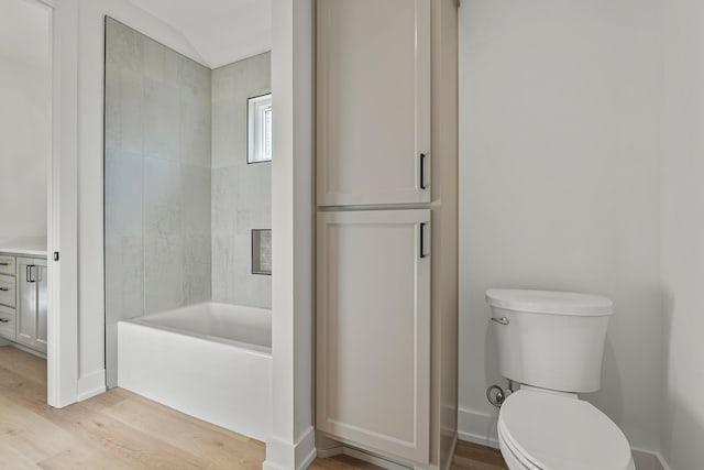 bathroom featuring a washtub, hardwood / wood-style floors, and toilet