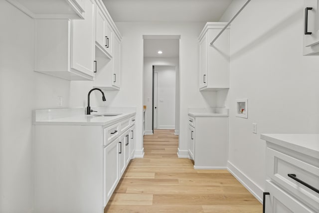 clothes washing area with washer hookup, sink, and light hardwood / wood-style floors