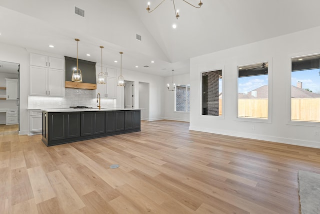 kitchen with white cabinetry, a chandelier, a kitchen island with sink, and pendant lighting