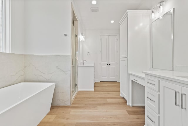 bathroom with hardwood / wood-style flooring, vanity, independent shower and bath, and tile walls