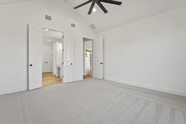 unfurnished bedroom featuring ceiling fan, light colored carpet, connected bathroom, and high vaulted ceiling