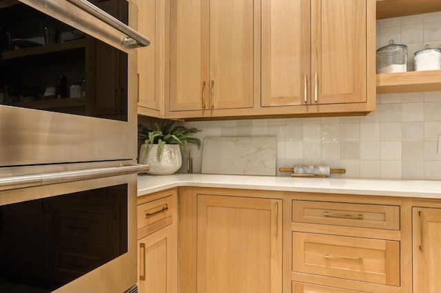 kitchen with tasteful backsplash, stainless steel double oven, and light brown cabinets