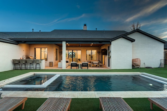 back of house featuring an outdoor hangout area, an outdoor bar, a patio, and a lawn