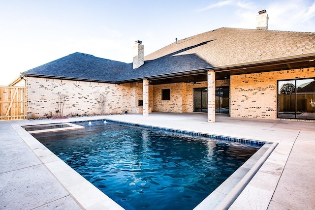 view of swimming pool featuring a patio area, fence, and a pool with connected hot tub