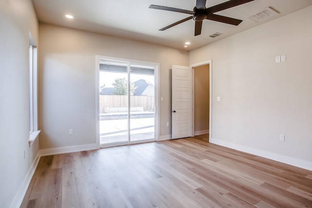 spare room with baseboards, visible vents, ceiling fan, and wood finished floors