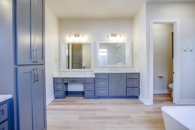 bathroom featuring vanity, wood finished floors, toilet, and baseboards