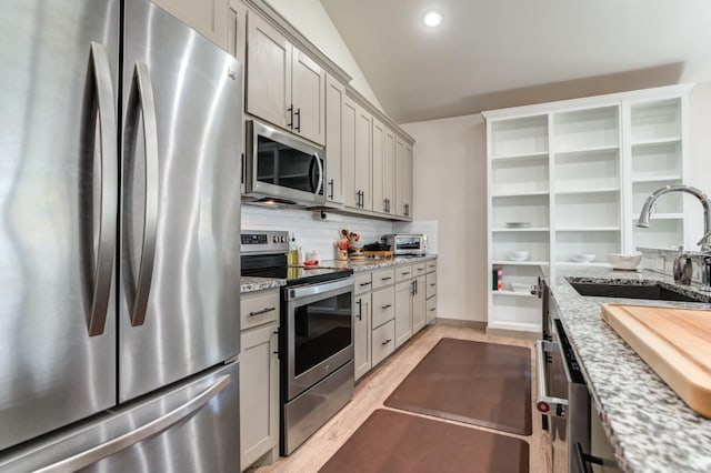 kitchen with light stone counters, stainless steel appliances, sink, and gray cabinetry