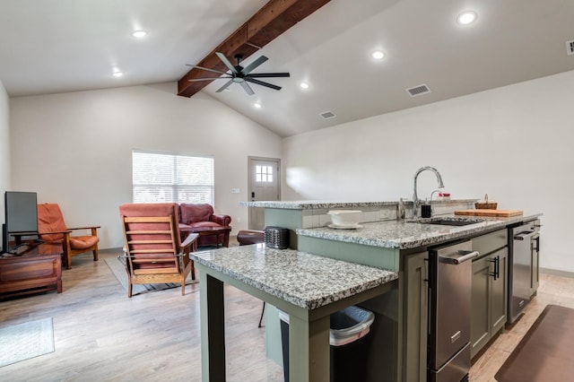 kitchen featuring sink, vaulted ceiling with beams, light stone counters, a center island with sink, and light hardwood / wood-style floors