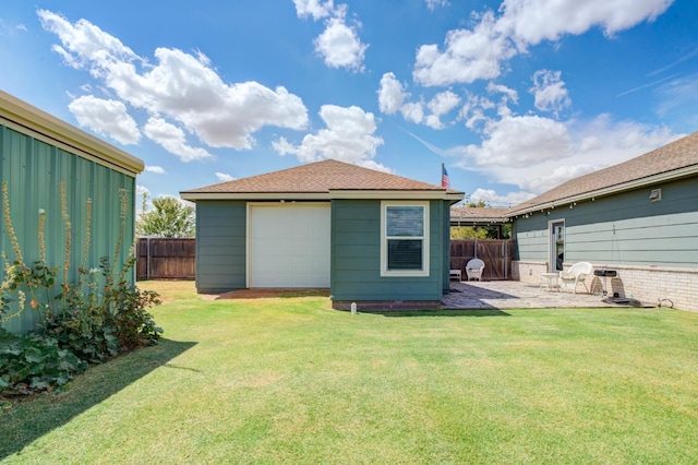 rear view of property with an outbuilding, a garage, a yard, and a patio