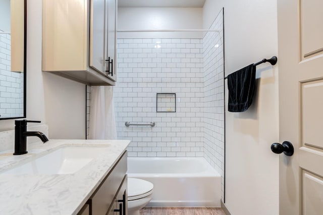 full bathroom featuring wood-type flooring, toilet, tiled shower / bath combo, and vanity