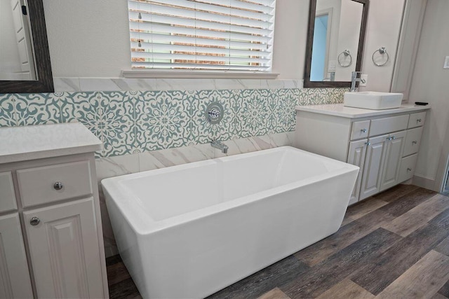 bathroom featuring a soaking tub, tile walls, vanity, and wood finished floors