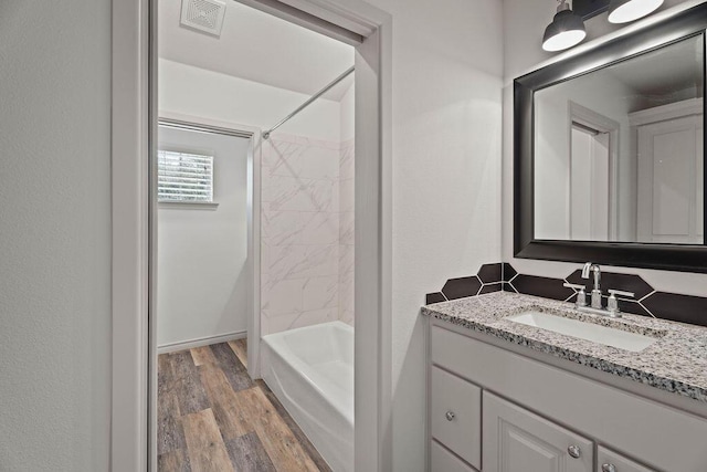 bathroom with vanity, shower / bath combination, wood finished floors, and visible vents