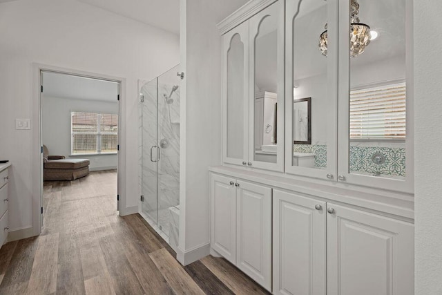 bathroom featuring a marble finish shower, baseboards, wood finished floors, and vanity