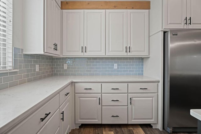 kitchen with stainless steel fridge, dark wood finished floors, white cabinets, and decorative backsplash