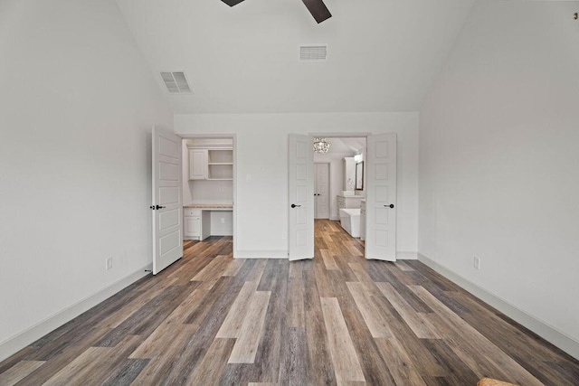 unfurnished bedroom featuring lofted ceiling, a spacious closet, visible vents, and wood finished floors