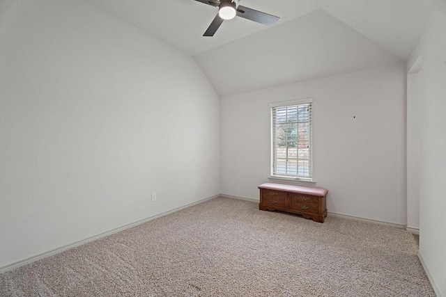 spare room with vaulted ceiling, light carpet, a ceiling fan, and baseboards