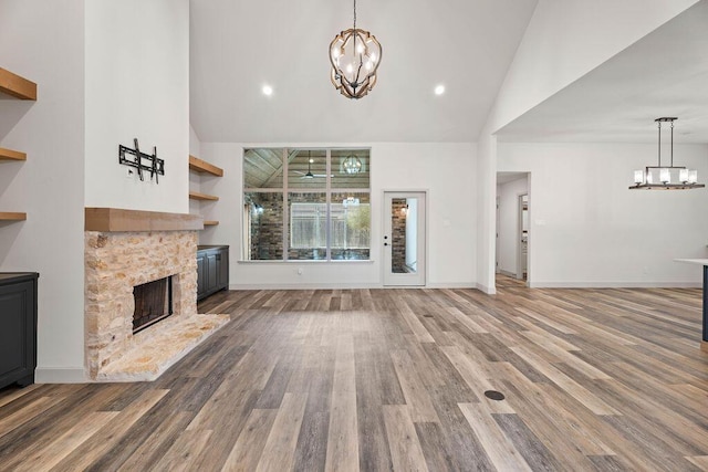 unfurnished living room featuring a chandelier, a fireplace, and wood finished floors